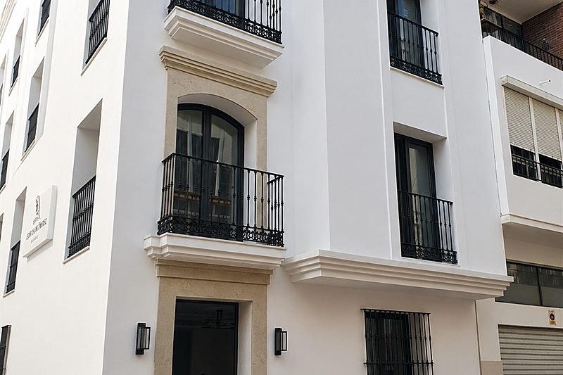 Fachada del edificio con balcones de forja, molduras y carpintería en negro