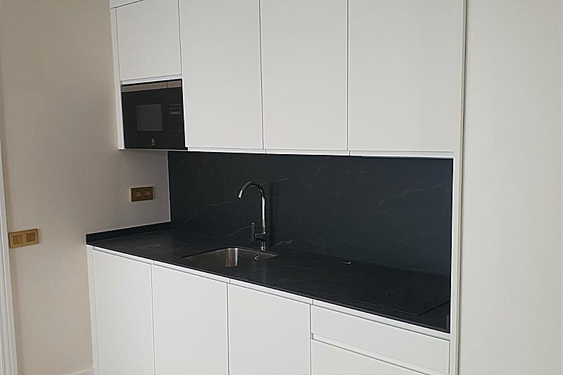 Cocina con frente lacado en blanco y encimera en tono oscuro
