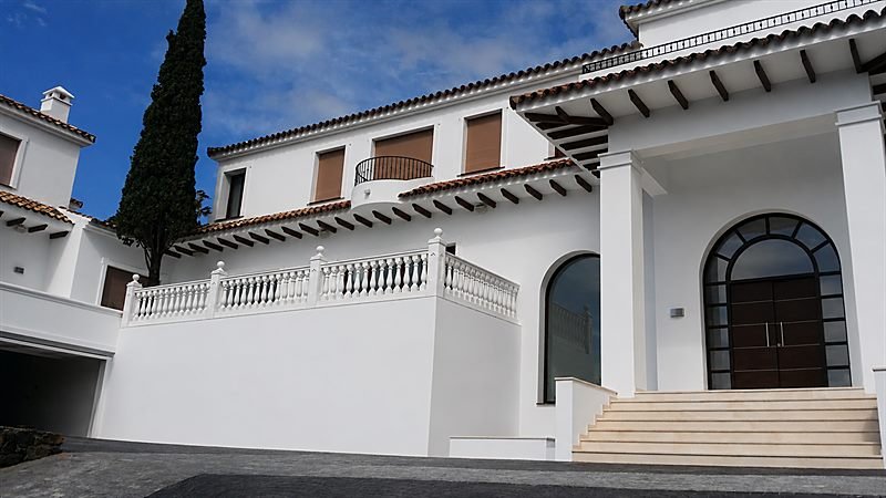 Fachada principal de la villa reformada en El Madroñal, con acceso porticado y escalera de piedra